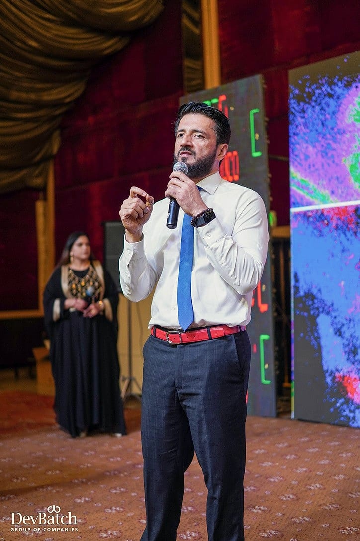Waqas Khan Pitafi speaking with a microphone at a DevBatch company event